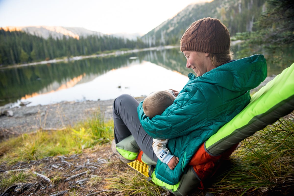 Mamá alimentando al bebé con el biberón en un viaje de acampada